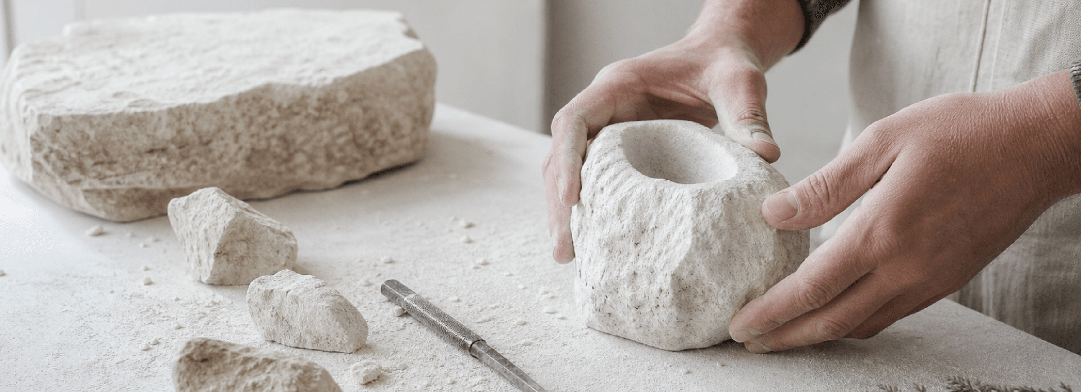 Hands shaping a natural stone vessel