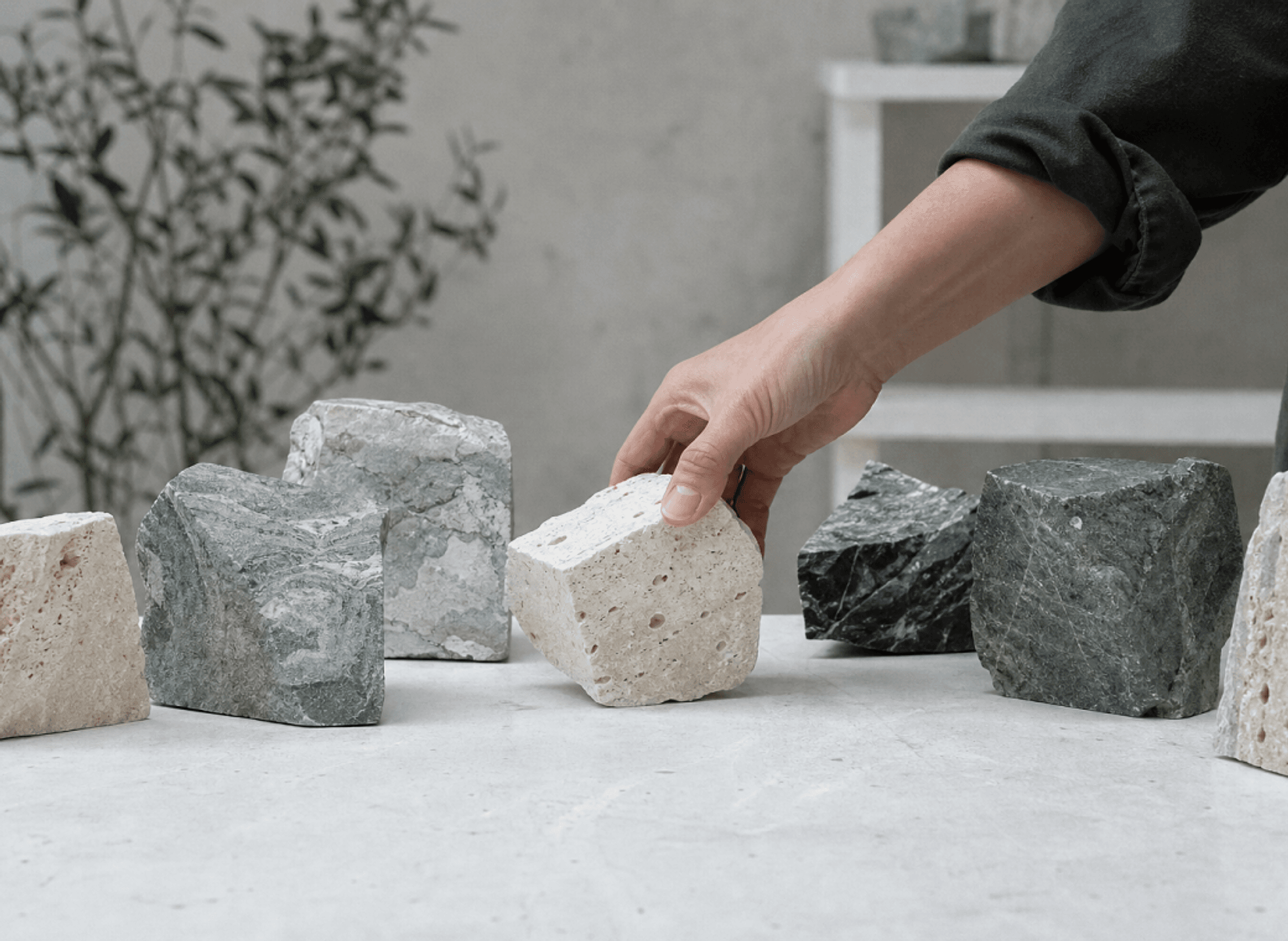 A hand selecting stone blocks in the studio