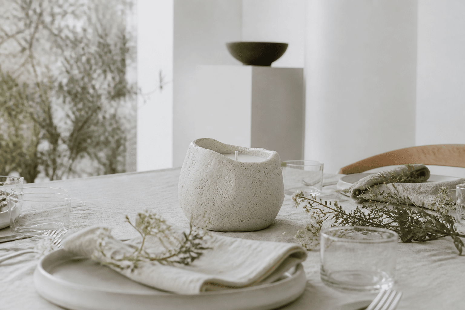 A stone candle set on a pale table for a returning seasonal ritual